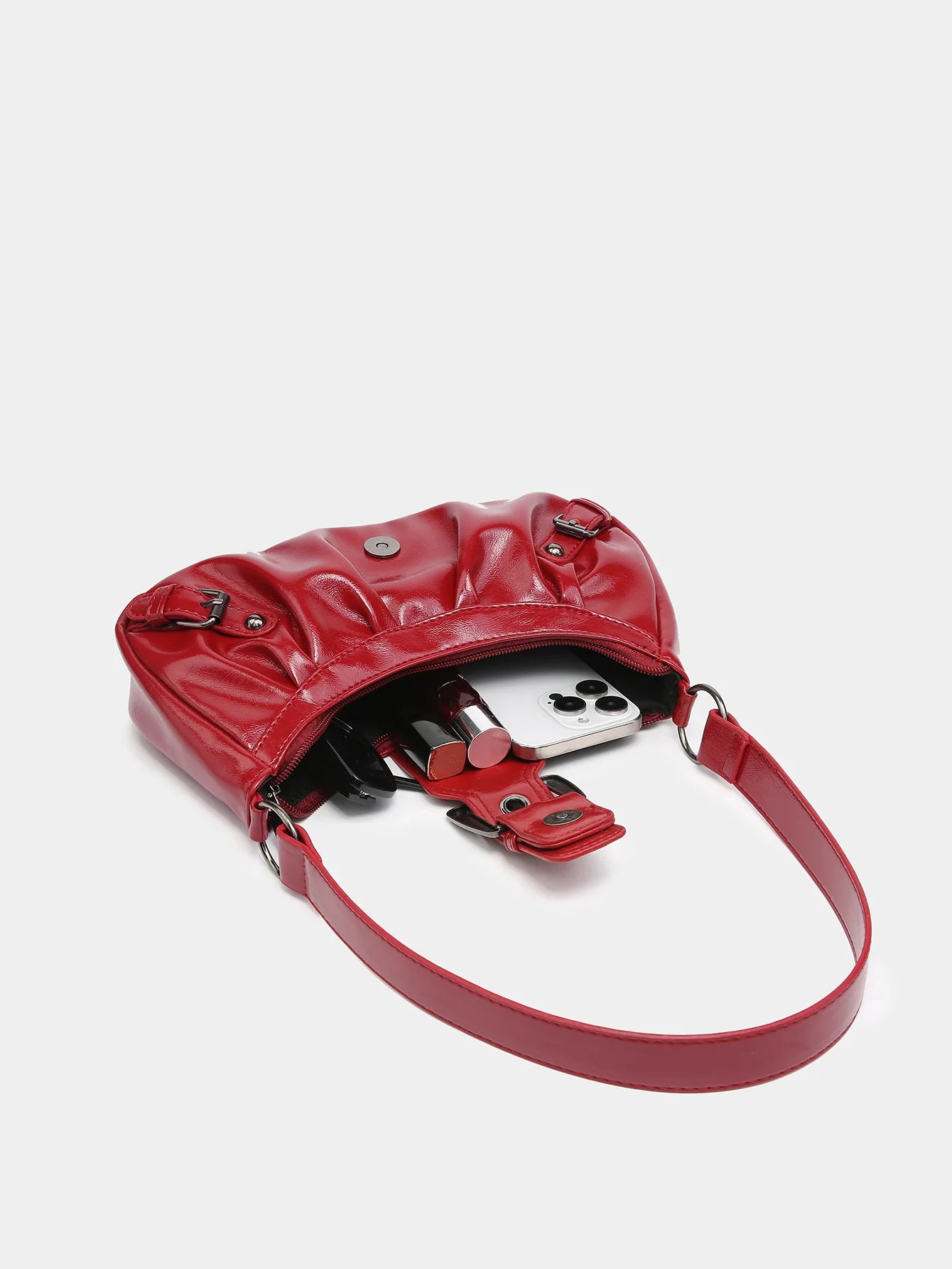 Red Y2K style leather shoulder bag showcasing contents inside, including lipstick and a smartphone.